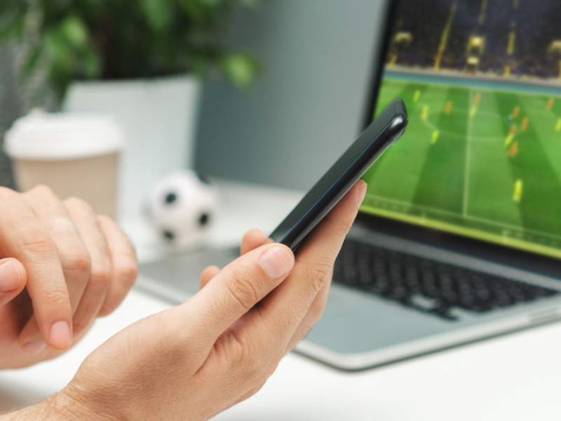 pessoa no celular apostando e vendo jogo