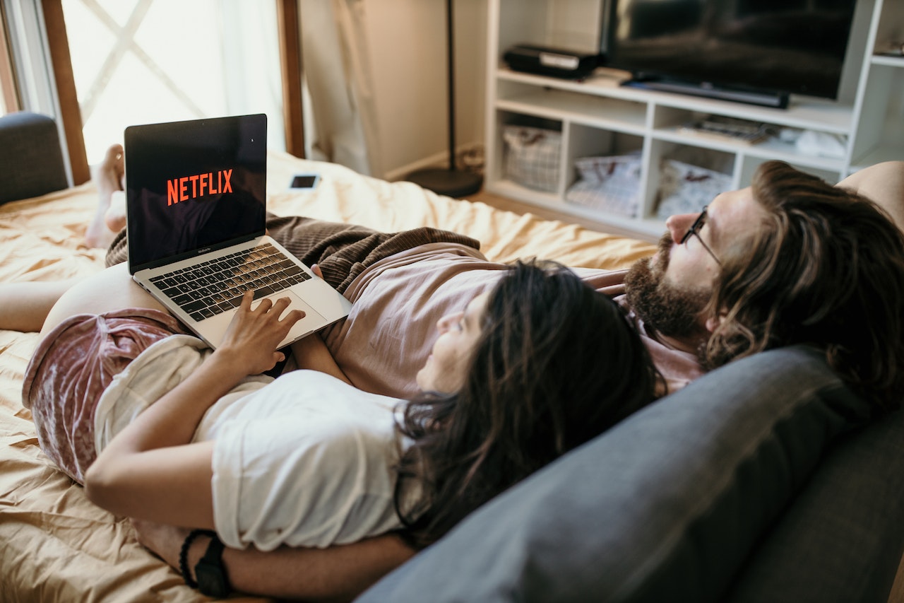 casal de namorados na cama com o notebook aberto assistindo netflix